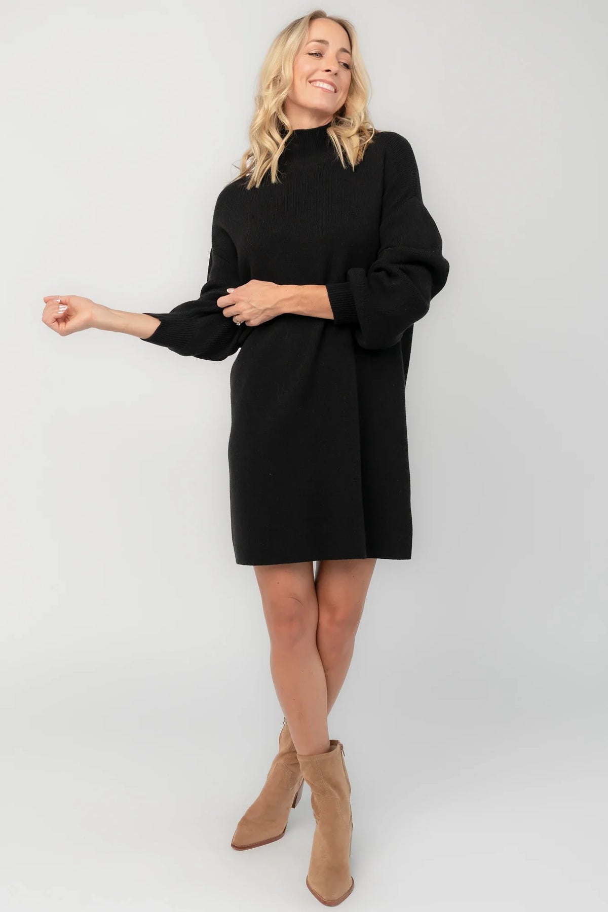 Black knit sweater dress with a mock neckline, long balloon sleeves, dropped shoulders, and a relaxed above-the-knee silhouette.