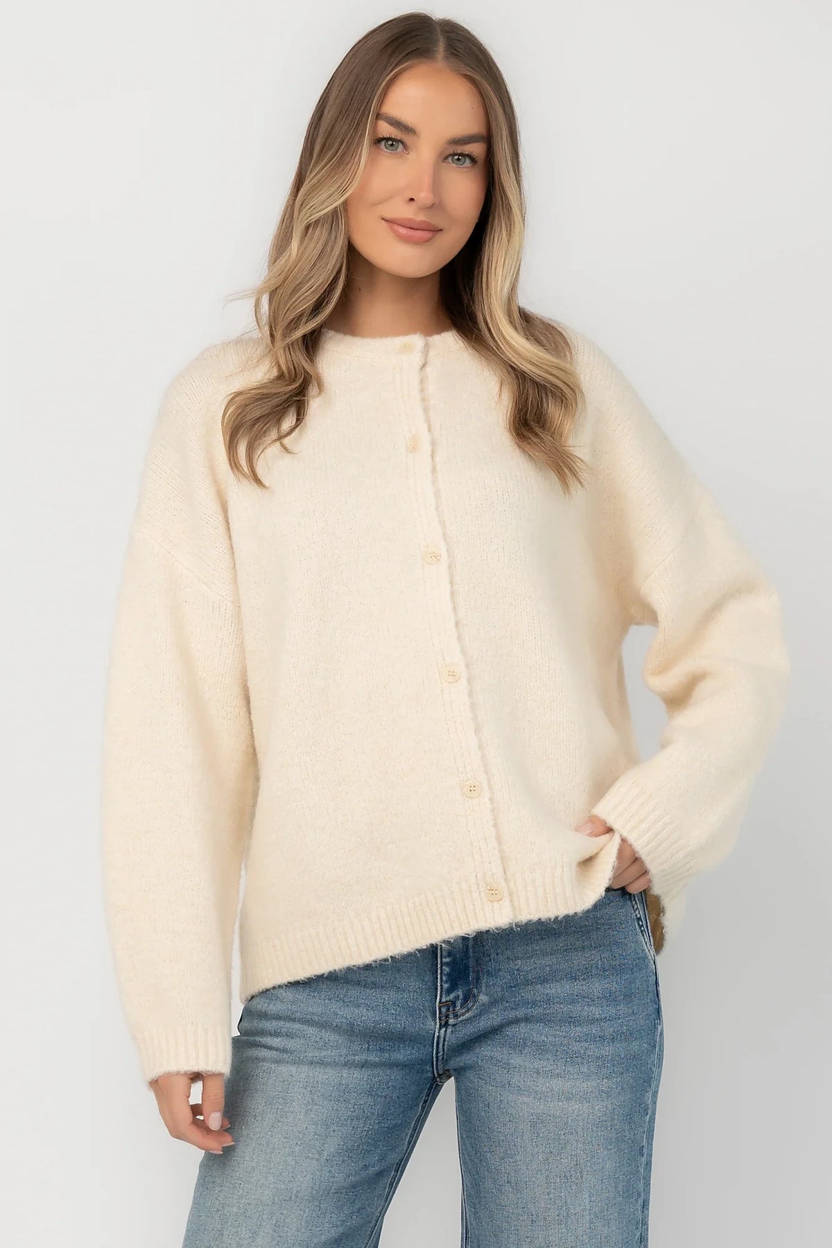 Cream fuzzy knit cardigan with a round neckline, button-front closure, long sleeves, dropped shoulders, and a relaxed fit.